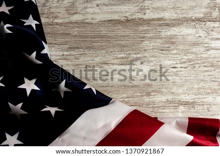 Overhead picture of united states flag at the left side on wooden table, creating a frame, and free space at the right side
