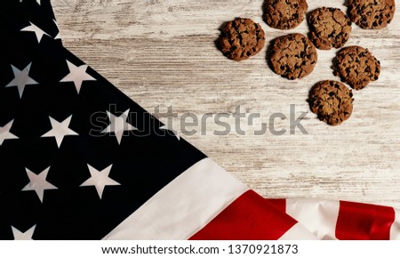 Overhead picture of united states flag at the left side, cookies at the right side, all on wooden table