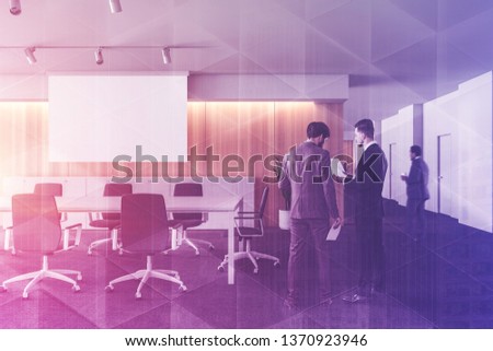 Business people discussing work in stylish conference room interior with wooden walls, panoramic windows, long table and white projection screen. Toned image double exposure
