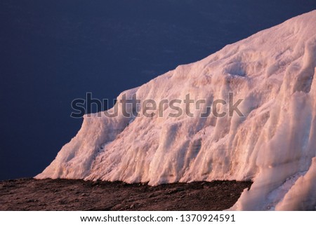 Blue dark sky and ground. Big ice and snow hill. Winter picture of the nature places.