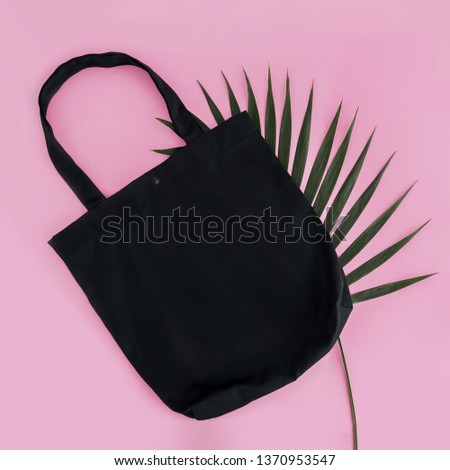 Black cotton bag and palm leaf on pink background. Mock up for design.