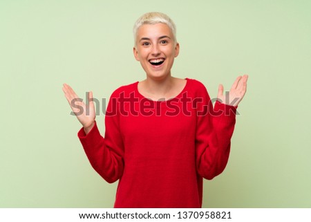 Teenager girl with white short hair over green wall with shocked facial expression
