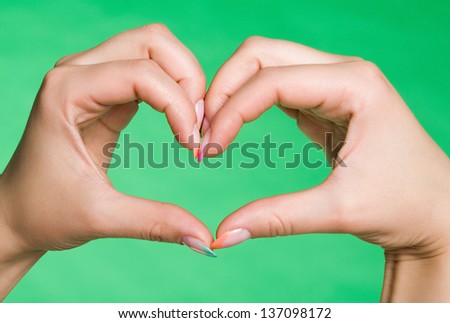 Hands show heart on green background