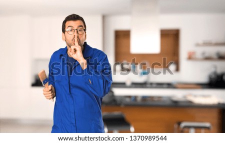 Painter man showing a sign of silence gesture putting finger in mouth at home