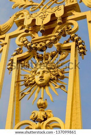 Golden ornate gate of Chateau de Versailles with blue sky
