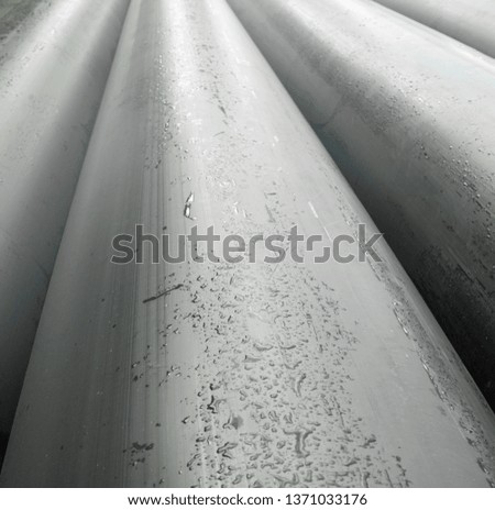 New gray metal pipes (tubes) surface. Wet metal after the rain. Pipeline construction.