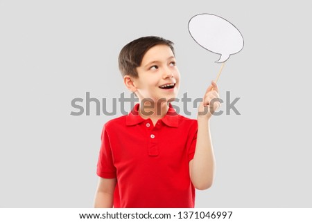 party props, photo booth and communication concept - smiling little boy in red polo t-shirt holding blank speech bubble over grey background Royalty-Free Stock Photo #1371046997