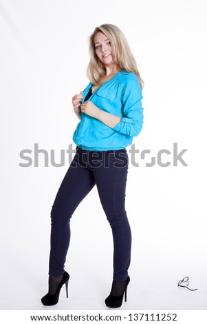 Beautiful blonde in a blue blouse and pants rehearsing a photo shoot 