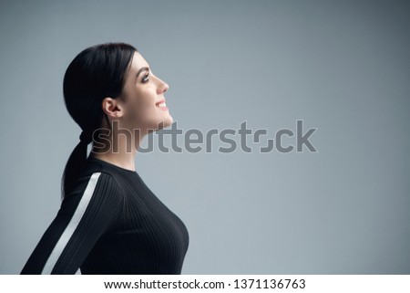 Closeup profile portrait of smiling woman looking up at blank copy space, over gray background