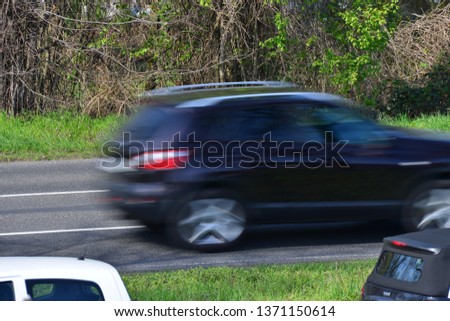 Cars driving by with green nature in the background
