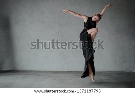 Young modern dancer in black dress. trains and dances in a gray studio Royalty-Free Stock Photo #1371187793