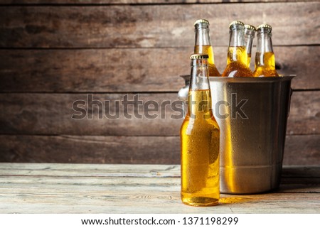 Cold bottles of beer in the bucket on the wooden background Royalty-Free Stock Photo #1371198299