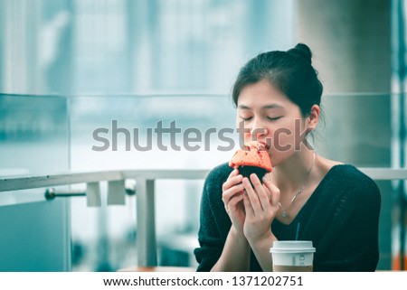 Asian woman eating muffin in cafe 