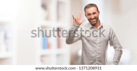 Caucasian man on grey brackground doing a rock gesture