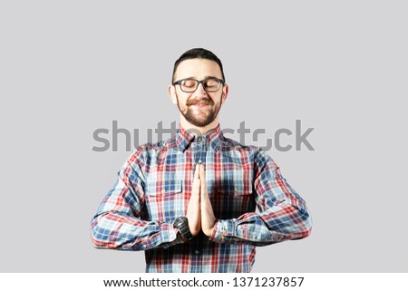 Young handsome man with facial hair posing over gray wall with a lot of copy space for text. Portrait of confident bearded male, wearing hipster slim fit checkered shirt. Isolated, background.