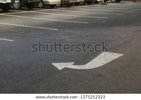 Closeup of arrow on asphalt ground of the parking lot after raining. The traffic sign show the symbol of safty and right direction to the goal.
