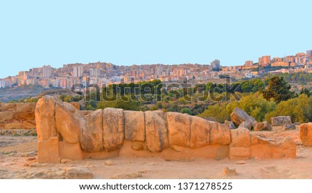 Italy, Sicily island, the valley of the temples of Agrigento, a Telamon, ruin of the giant statue of the temple of Zeus Olympios against Agrigento skyline on hill in background.