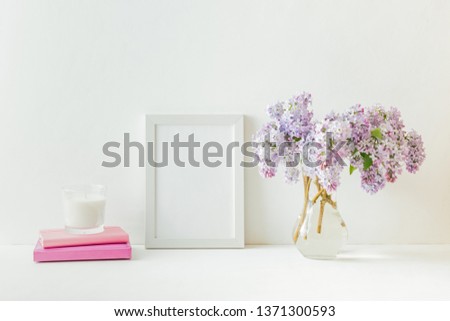 Mockup with a white frame and branches of lilac in a vase on a light background