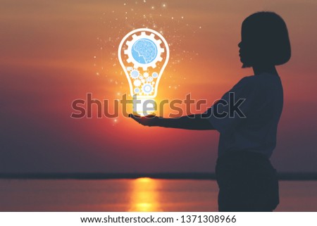 Creative idea and innovation concept, Woman hand holding light bulb on beautiful sunset background