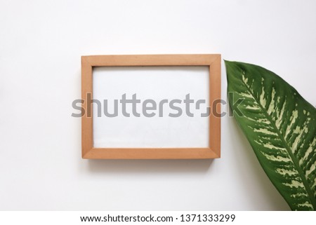 
blank frame is decorated with tropical leaf  on white background.  top view. Poster mockup. Clean, modern, minimal frame. 
