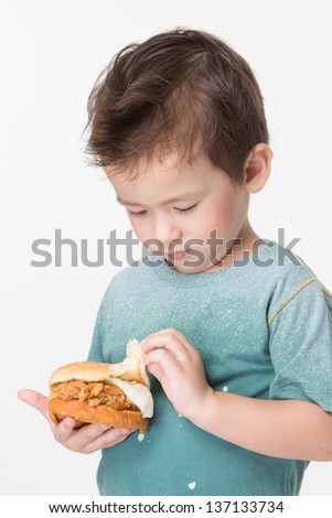 Handsome boy eating a big burger.