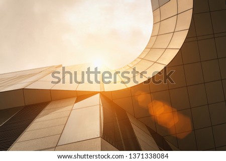 low angle view of modern golden architecture exterior with curve and sun flares above Royalty-Free Stock Photo #1371338084