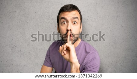 Handsome man showing a sign of silence gesture putting finger in mouth over textured wall