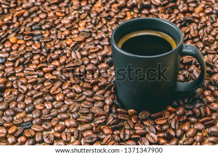 Espresso coffee in a black glass with coffee beans on a wooden table