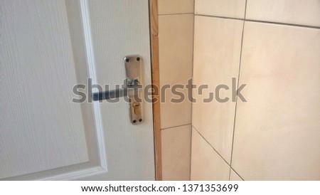 Texture, background, wallpaper, image of a white wooden door with a metal handle near the concrete tiles in any public building in the middle of the day.