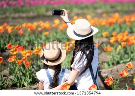 Mother and daughter taking pictures in the flower field