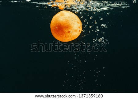 Orange fruit and water splash with bubbles on dark background
