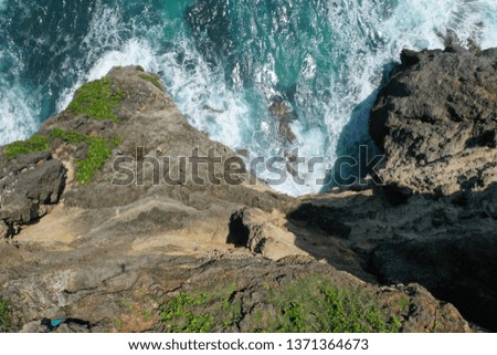 Aerial photo of green cliff and blue ocean with breaking waves in Uluwatu Temple, Bali, Indonesia.