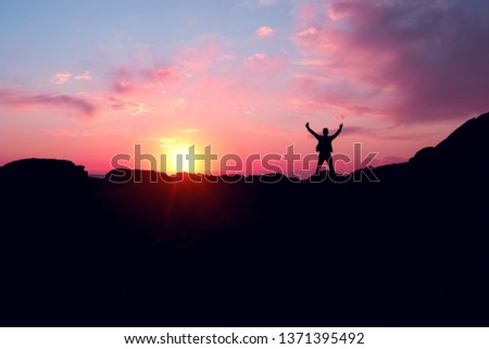 Black silhouette of a man and a mountain,with beautiful sunset and pink clouds.