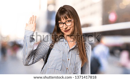 Woman with glasses saluting with hand with happy expression at outdoors