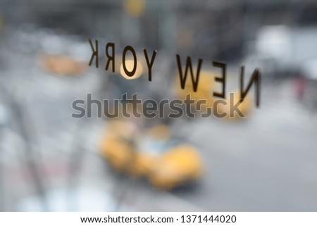 NYC inscription on the window overlooking the road with car and taxi