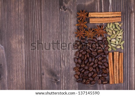 Coffee beans, cinnamon, star anise, cardamom on wood background