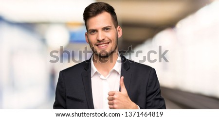 Handsome business man giving a thumbs up gesture and smiling at indoors