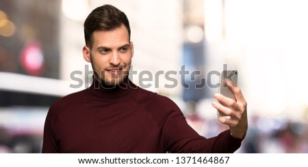 Man with turtleneck sweater making a selfie in the city