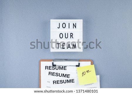 Creative top view flat lay of desk with Join our team text on lightbox with copy space on blue background in minimal style. Concept of new job, hiring recruitment process, new team members screening