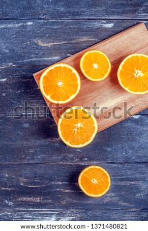 Creative dark style flat lay top view of fresh orange fruit slices on cutting board on brown wooden table background with copy space. Minimal summer fresh citrus composition for blog or recipe book