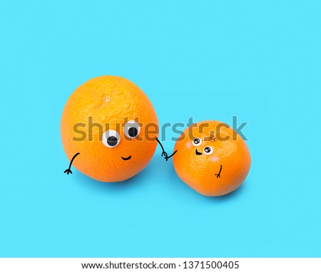 Funny food - two tangerines, small and big, on blue background. symbol of baby and parent. Tangerines with smile and eyes, Friendly Faces. creative idea, minimal kawaii style