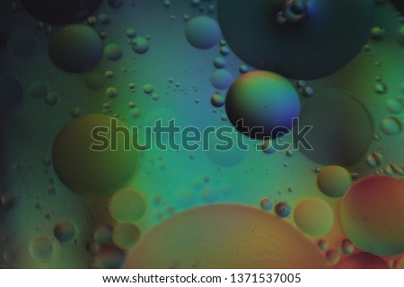 Holographic neon floating oil bubbles on watery surface.