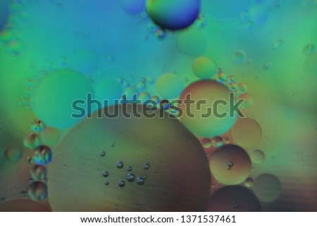 Holographic neon floating oil bubbles on watery surface.