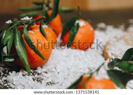 Mandarin citrus fruit with leaves on a wooden kitchen table on a blurred background. healthy food. raw food Artificial white snow. New Year. Christmas.