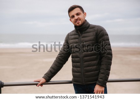 Handsome man standing in front of North Sea. Stylish man in khaki jacket