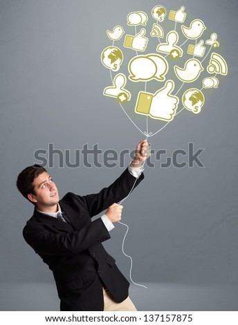 Attractive young man holding social icon balloon