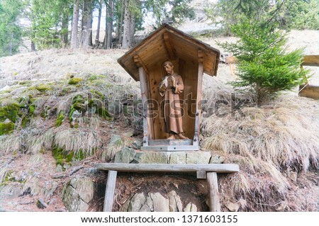A wood carved catholic statue of a holy monk in the forest of tyrol in the dolomites
