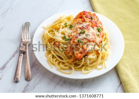Italian baked bruschetta chicken served over spaghetti noodles Royalty-Free Stock Photo #1371608771