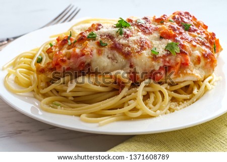 Italian baked bruschetta chicken served over spaghetti noodles Royalty-Free Stock Photo #1371608789