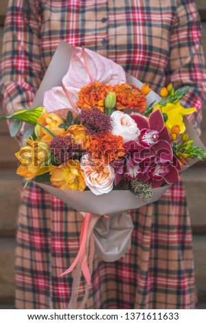 Rustic flowers bouquet of mixed assorted flowers in modern composition in paper on wooden background with copy text.